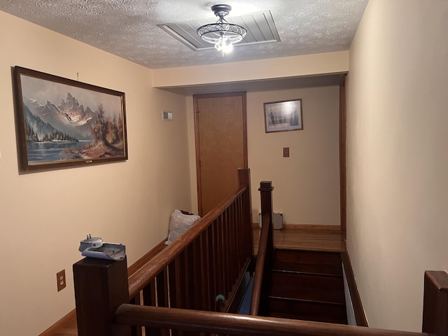 stairs with baseboards, a textured ceiling, and wood finished floors