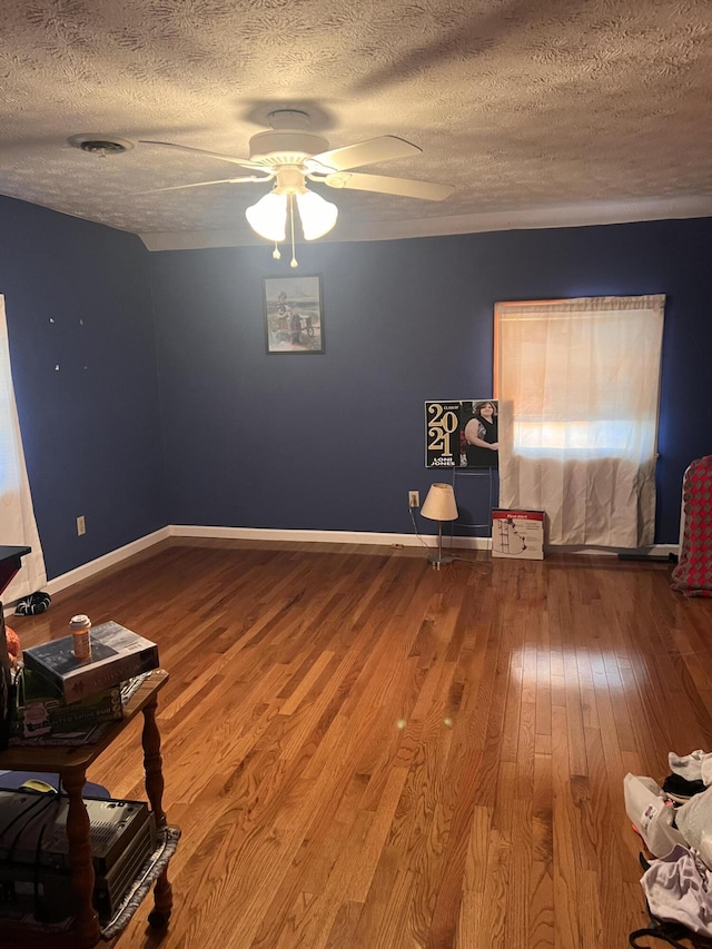 spare room featuring a ceiling fan, a textured ceiling, baseboards, and hardwood / wood-style flooring