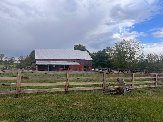 view of yard with an outbuilding, a rural view, fence, and a barn