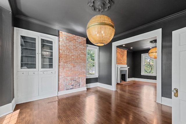 unfurnished living room featuring brick wall, a fireplace, crown molding, and dark hardwood / wood-style flooring