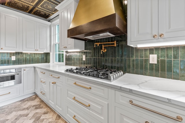 kitchen with backsplash, white cabinets, stainless steel appliances, and custom range hood