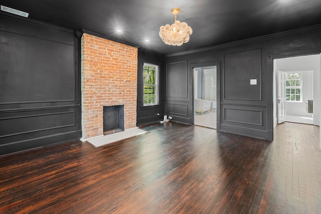 unfurnished living room with a brick fireplace, crown molding, and dark hardwood / wood-style flooring