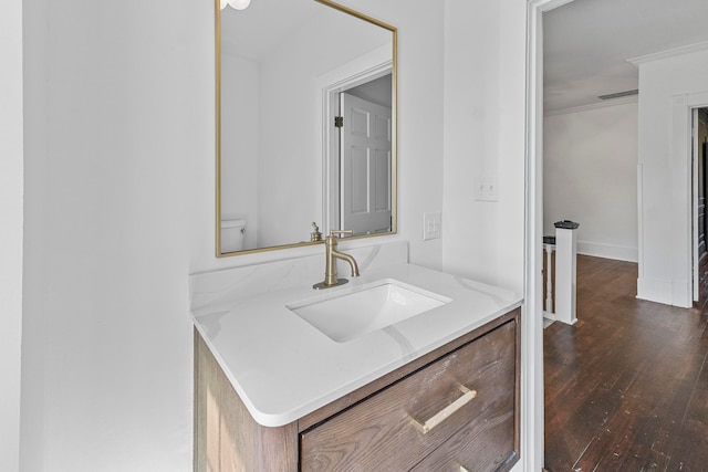 bathroom featuring ornamental molding, hardwood / wood-style floors, vanity, and toilet