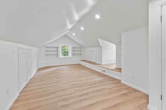 bonus room featuring lofted ceiling, built in shelves, and light wood-type flooring