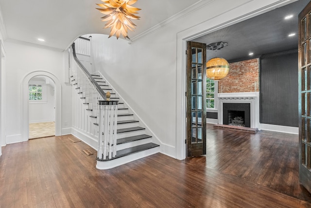 stairs with wood-type flooring, crown molding, and a chandelier