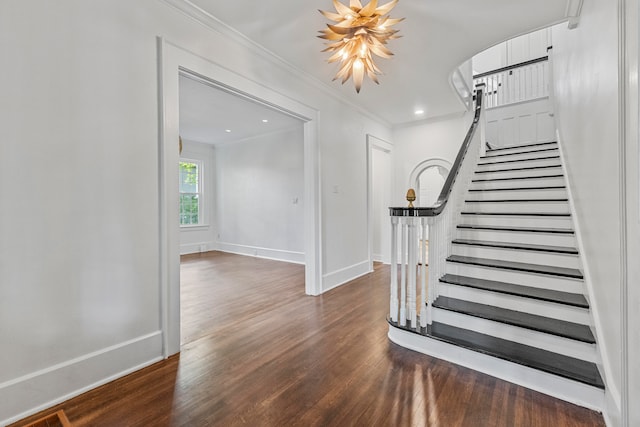 stairs featuring crown molding, hardwood / wood-style floors, and a notable chandelier