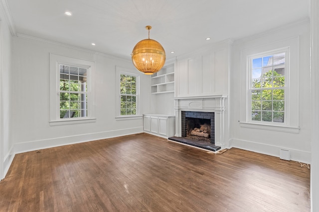 unfurnished living room featuring ornamental molding, a healthy amount of sunlight, a fireplace, and dark hardwood / wood-style floors