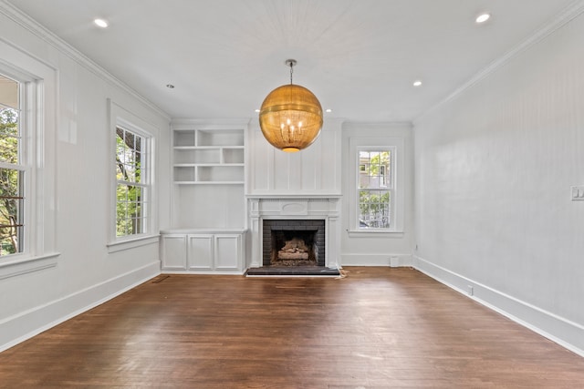 unfurnished living room with ornamental molding, a fireplace, built in shelves, and dark wood-type flooring