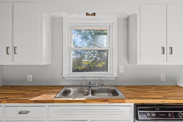 kitchen with wood counters, dishwasher, sink, and white cabinets