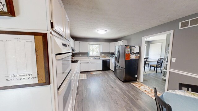 kitchen featuring dishwasher, hardwood / wood-style flooring, sink, stainless steel fridge with ice dispenser, and white cabinets