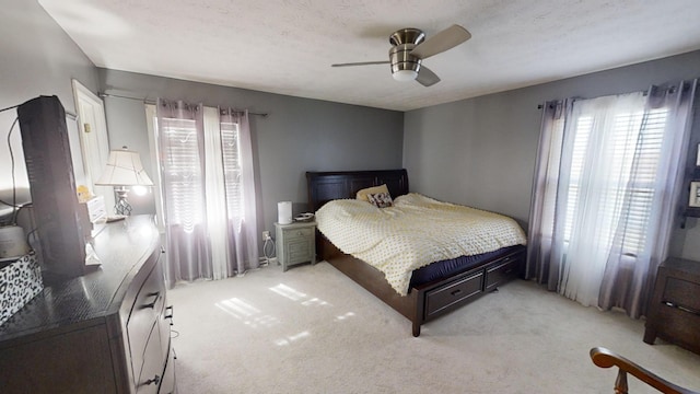 bedroom with a textured ceiling, light colored carpet, and ceiling fan