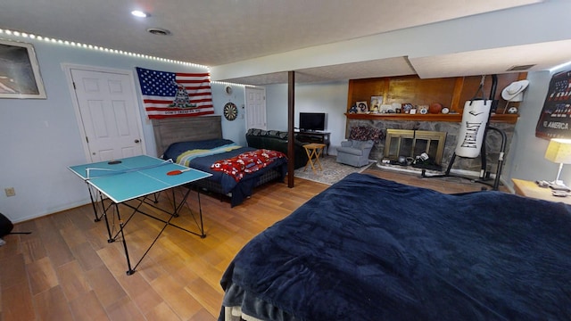 bedroom with hardwood / wood-style floors and a fireplace