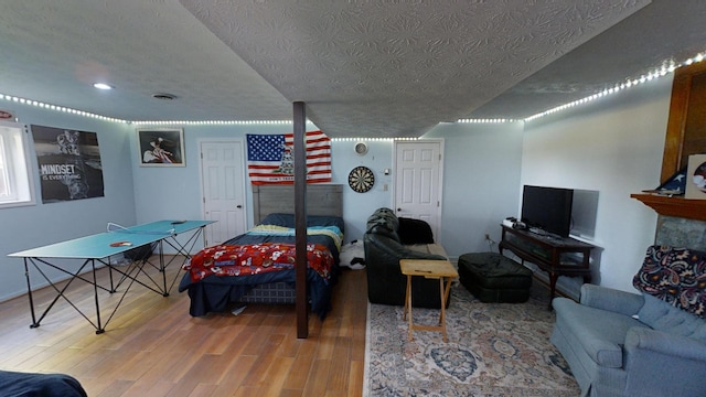 living room featuring a textured ceiling, wood-type flooring, and a fireplace