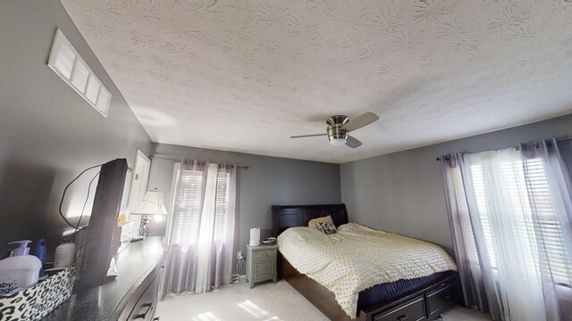 bedroom featuring a textured ceiling, light colored carpet, and ceiling fan