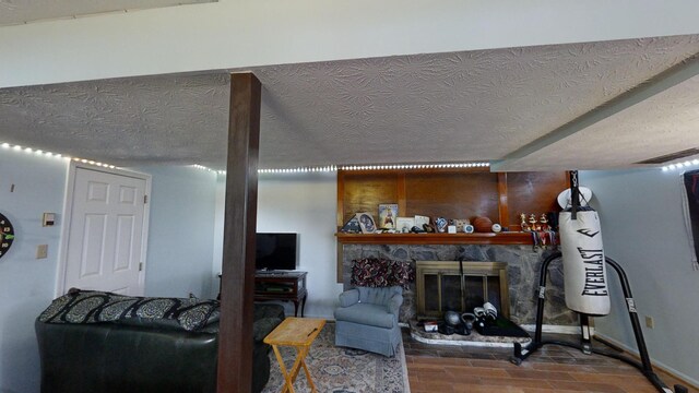 living room with a stone fireplace and a textured ceiling