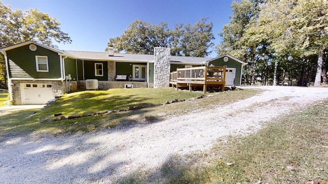 ranch-style home featuring a front yard, a deck, and a garage