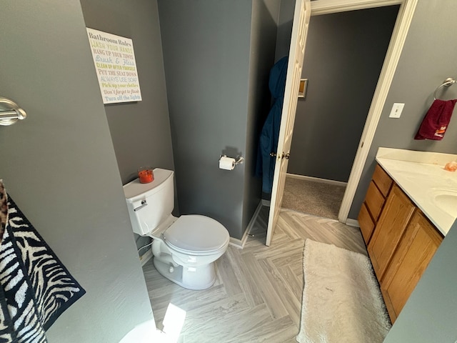 bathroom featuring toilet, vanity, and parquet flooring