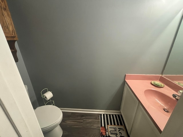 bathroom with toilet, hardwood / wood-style floors, and vanity