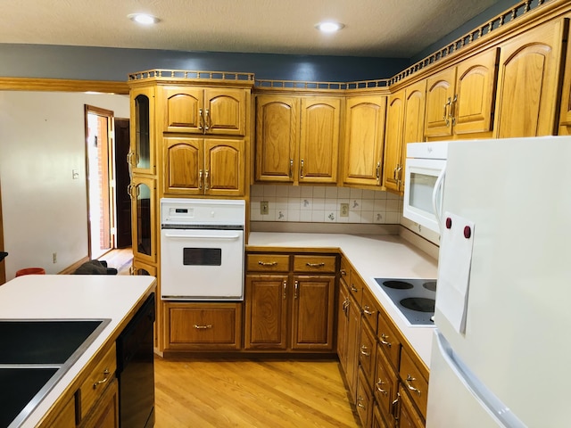 kitchen featuring tasteful backsplash, sink, white appliances, a textured ceiling, and light hardwood / wood-style flooring