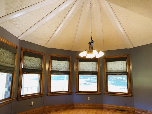 interior space featuring lofted ceiling with beams, wood-type flooring, and an inviting chandelier