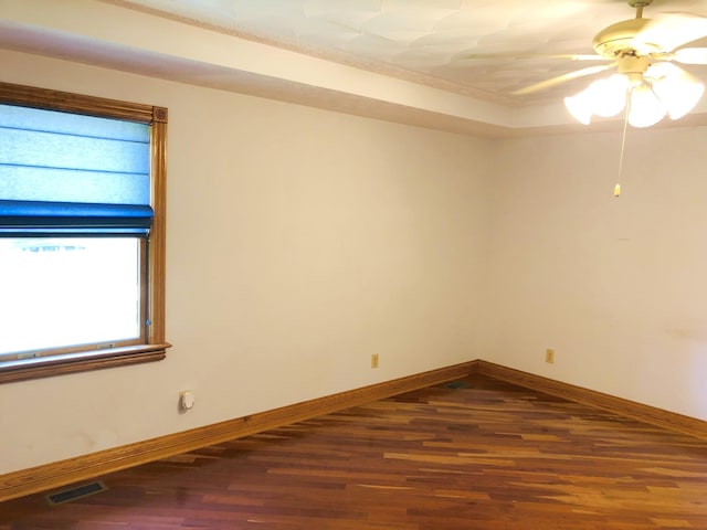 empty room featuring dark hardwood / wood-style floors, a raised ceiling, and ceiling fan