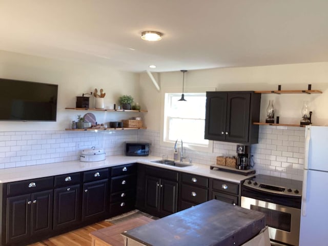 kitchen with sink, light hardwood / wood-style flooring, stainless steel range with electric cooktop, white fridge, and decorative backsplash