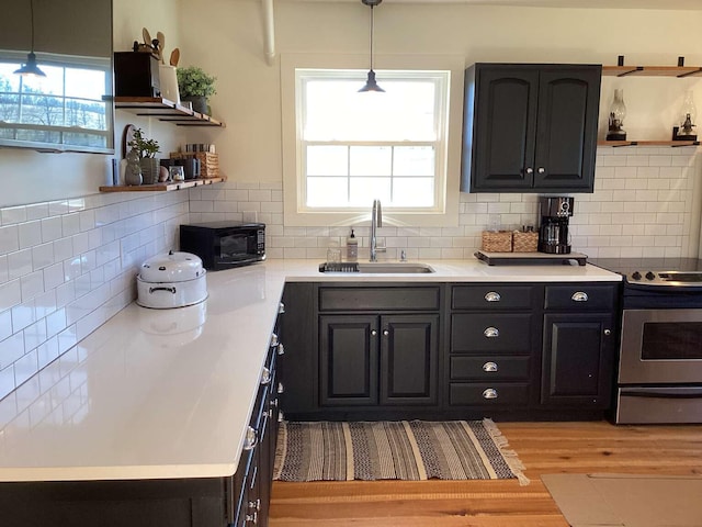 kitchen featuring hanging light fixtures, sink, a wealth of natural light, and stainless steel electric stove