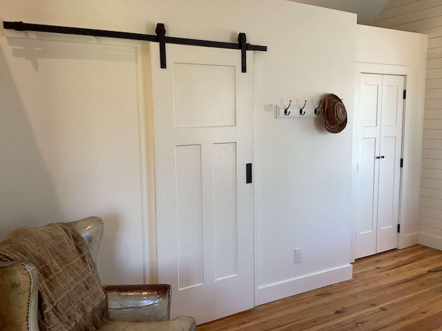 interior space with wood walls, a barn door, and hardwood / wood-style floors