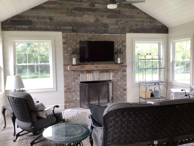 living room featuring hardwood / wood-style flooring, a wealth of natural light, vaulted ceiling, and a brick fireplace