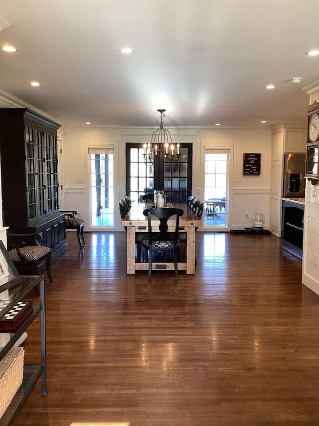 dining space featuring crown molding, dark wood-type flooring, and a chandelier