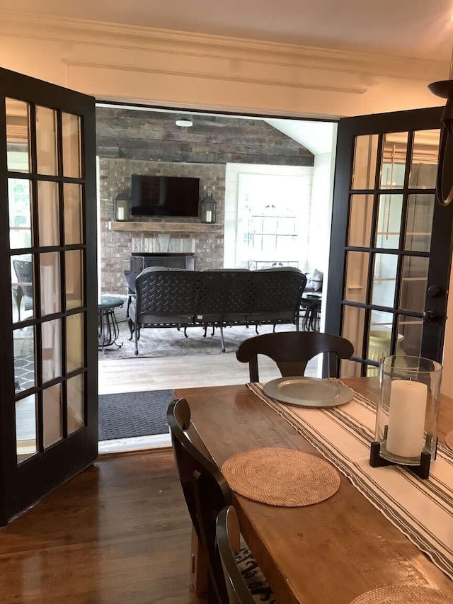 dining space with ornamental molding, hardwood / wood-style flooring, and a fireplace