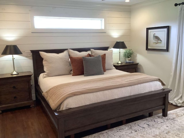 bedroom with ornamental molding, dark hardwood / wood-style flooring, and wooden walls