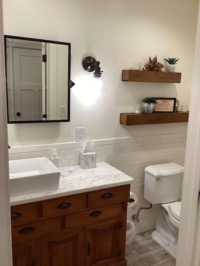 bathroom featuring vanity, tile walls, and toilet