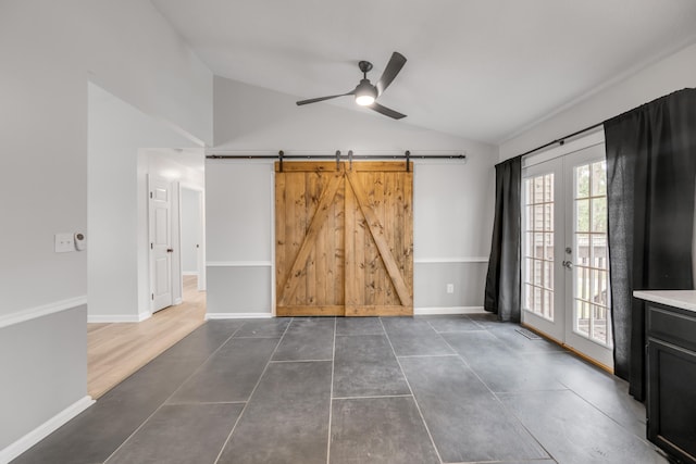 unfurnished room with ceiling fan, french doors, vaulted ceiling, a barn door, and dark hardwood / wood-style flooring