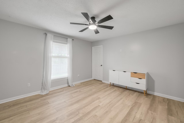 spare room with ceiling fan, light hardwood / wood-style floors, and a textured ceiling