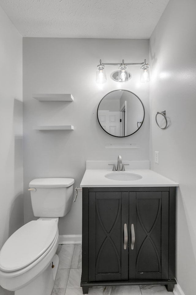 bathroom with a textured ceiling, vanity, and toilet