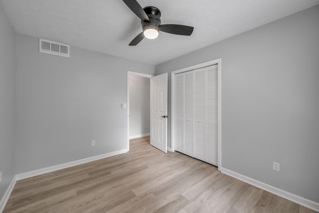 unfurnished bedroom featuring a closet, light hardwood / wood-style floors, a textured ceiling, and ceiling fan