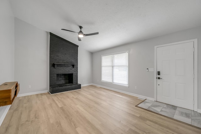 unfurnished living room featuring a brick fireplace, vaulted ceiling, light hardwood / wood-style flooring, and ceiling fan