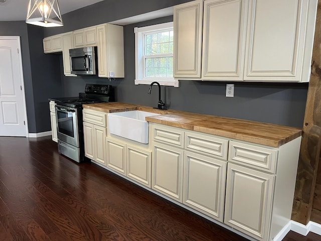 kitchen with butcher block countertops, baseboards, a sink, stainless steel appliances, and dark wood-style floors