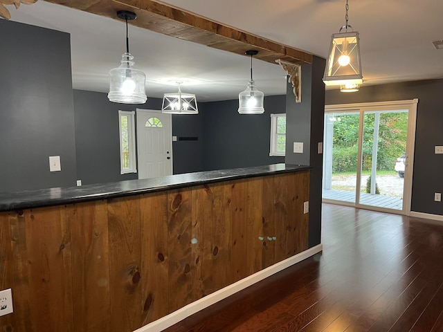 kitchen with brown cabinetry, baseboards, dark wood finished floors, pendant lighting, and dark countertops