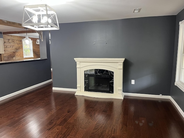 unfurnished living room with a fireplace, baseboards, visible vents, and wood finished floors
