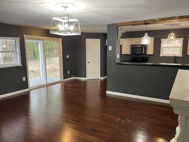 kitchen with stainless steel microwave, dark countertops, baseboards, and dark wood-style floors