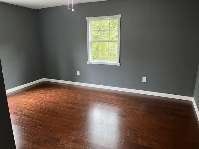 empty room featuring dark wood-style flooring and baseboards