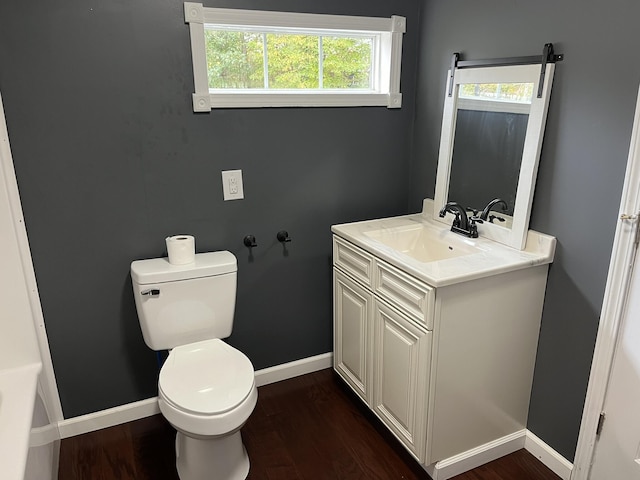 bathroom with toilet, baseboards, vanity, and wood finished floors