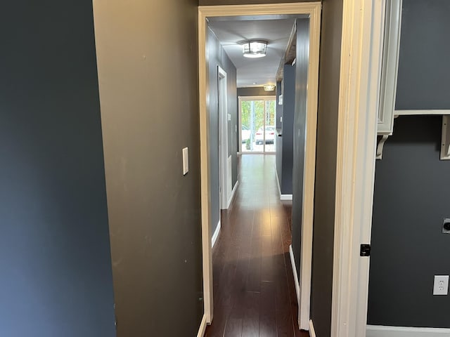 corridor with baseboards and dark wood-style floors