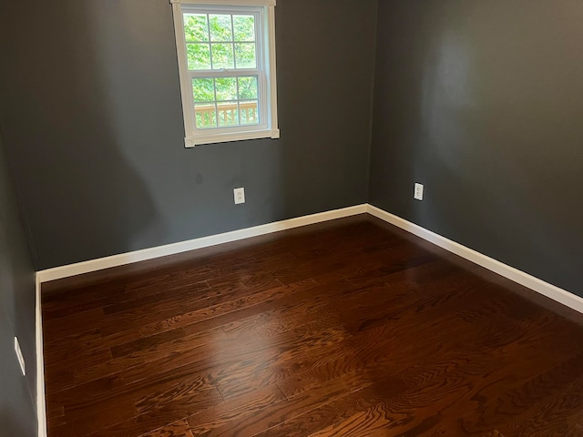 empty room with dark wood finished floors and baseboards