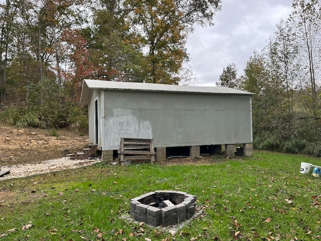 view of outbuilding featuring a fire pit and a lawn