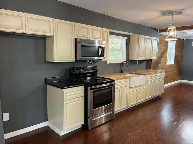 kitchen featuring wooden counters, dark wood-type flooring, appliances with stainless steel finishes, cream cabinets, and a sink