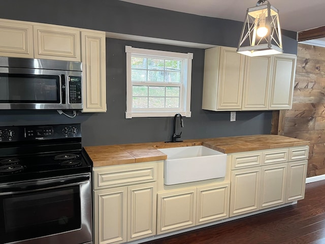 kitchen featuring stainless steel microwave, wooden counters, electric range, and a sink