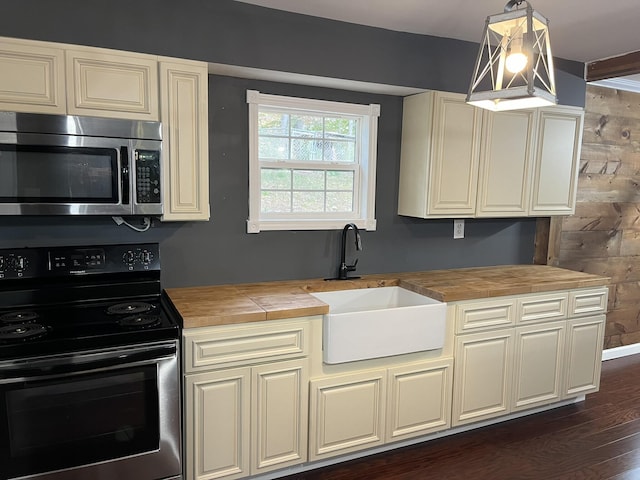 kitchen with electric range oven, wooden counters, a sink, and stainless steel microwave